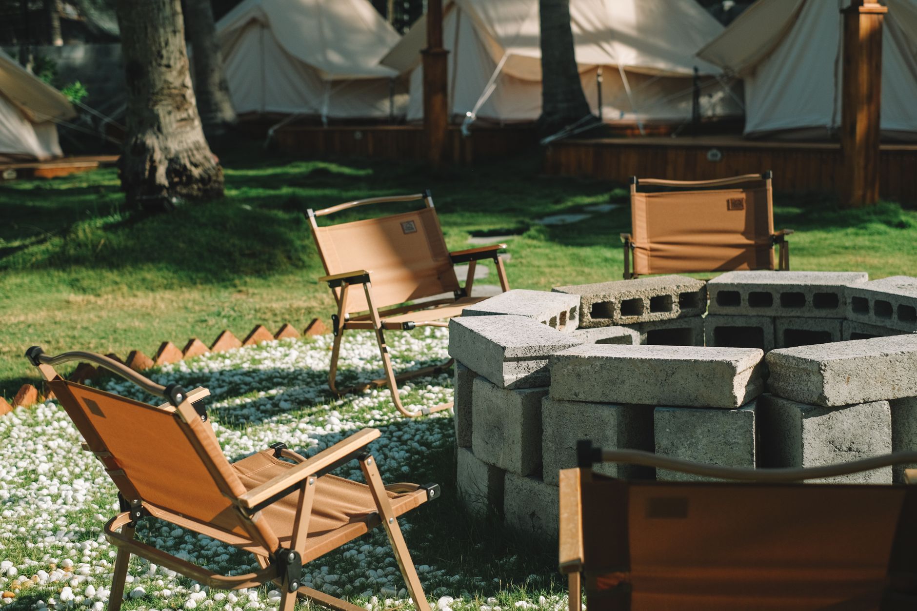 Outdoor fire pit with seating at a glamping site in the evening