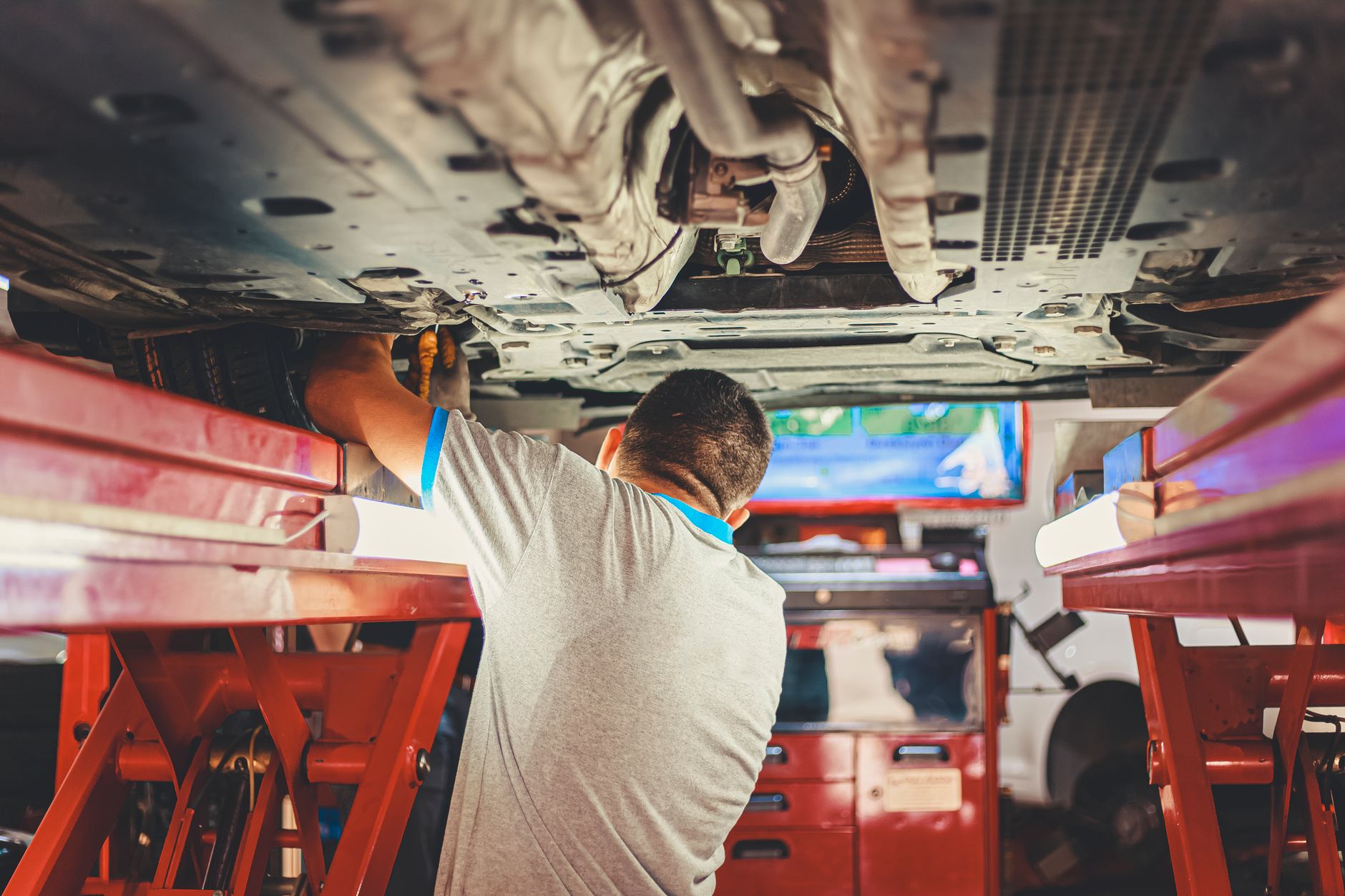 Mechanic working underneath a car on a ramp in a garage