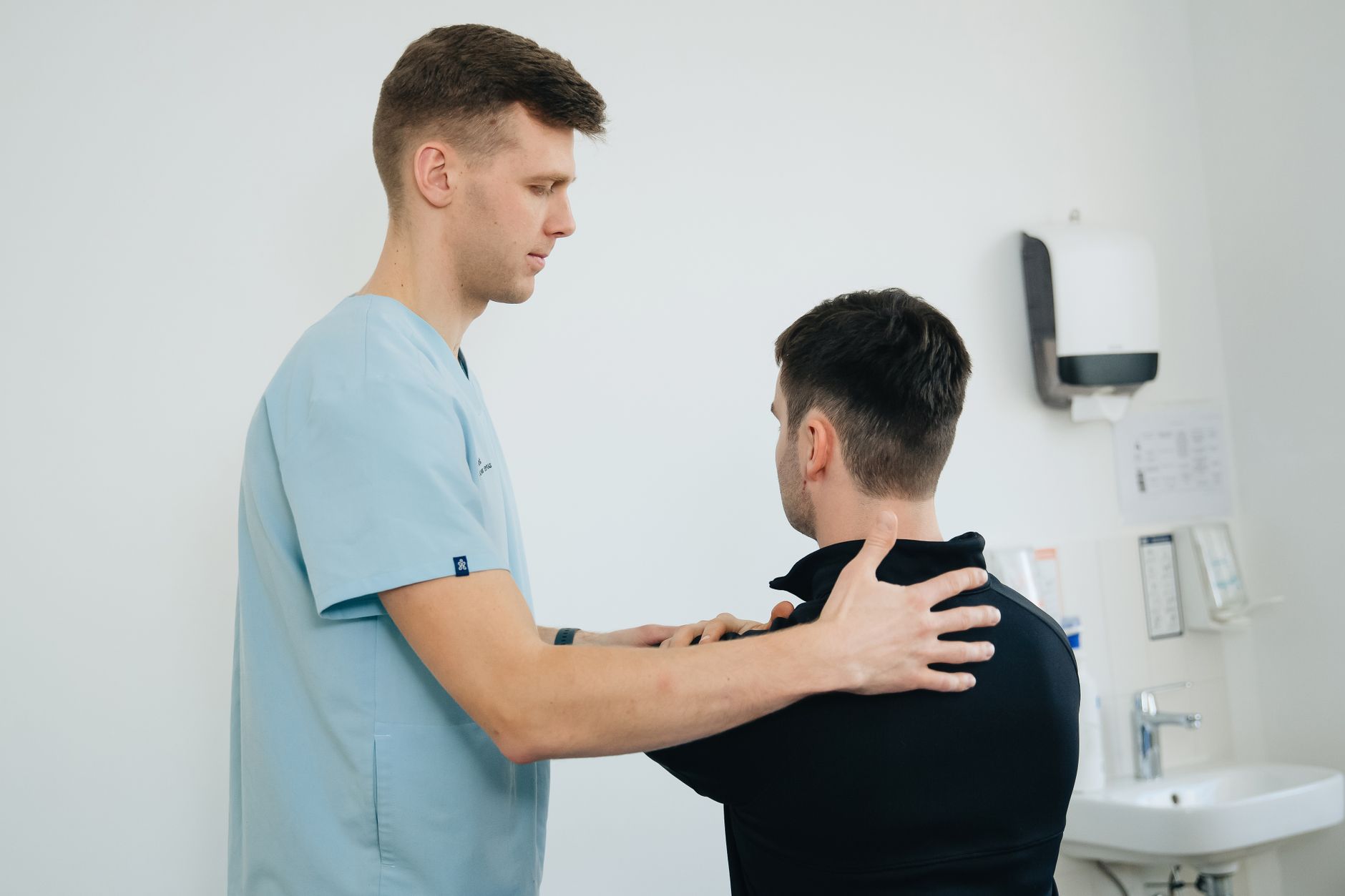 Physiotherapist treating a patient's shoulder in a clinic