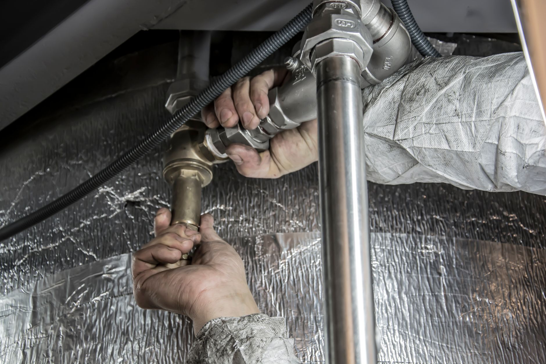 Plumber repairing a pipe under a kitchen sink